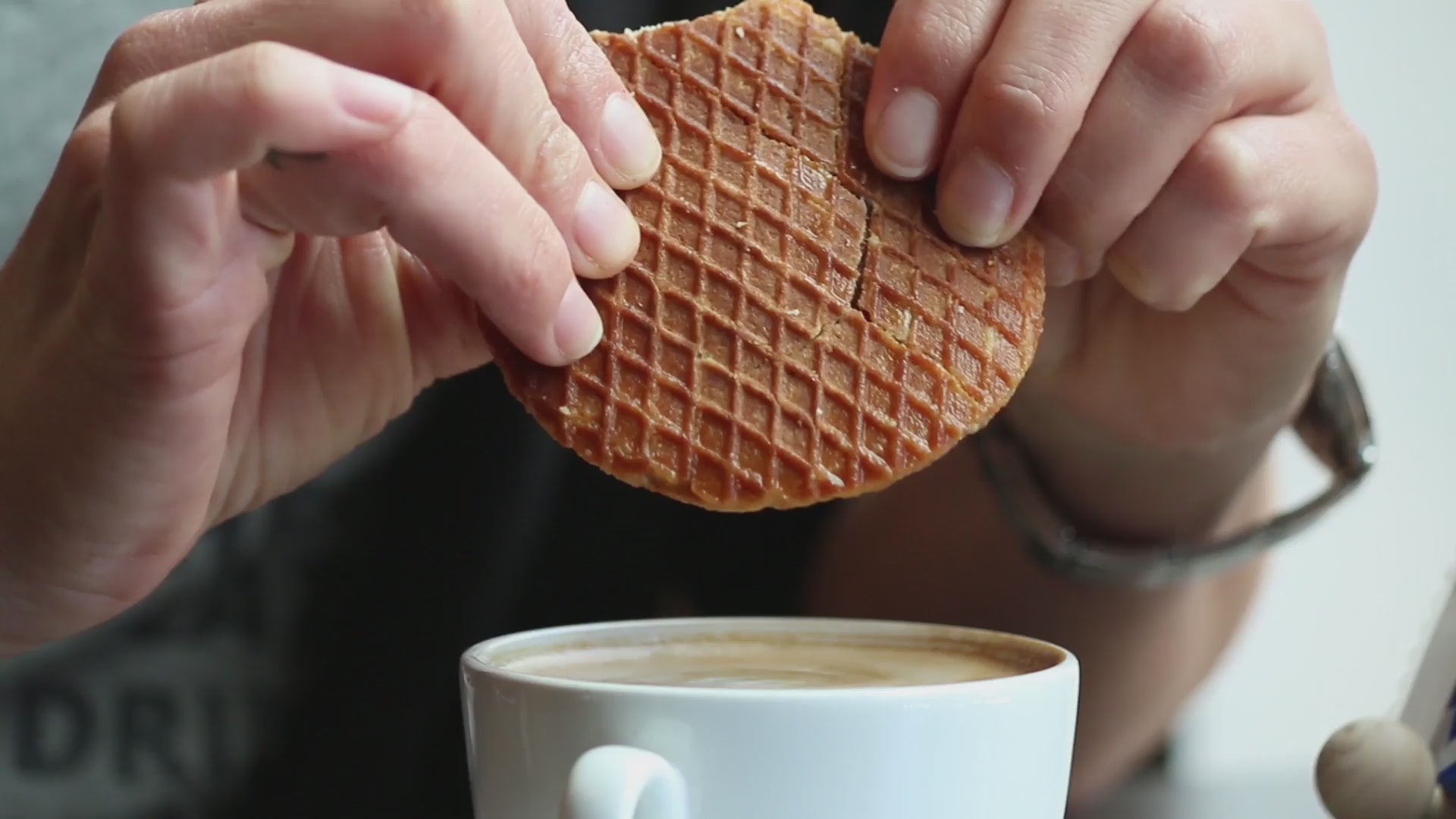 Load video: Video of a vegan stroopwafel and a cup of coffee, stroopwafel being broken in two